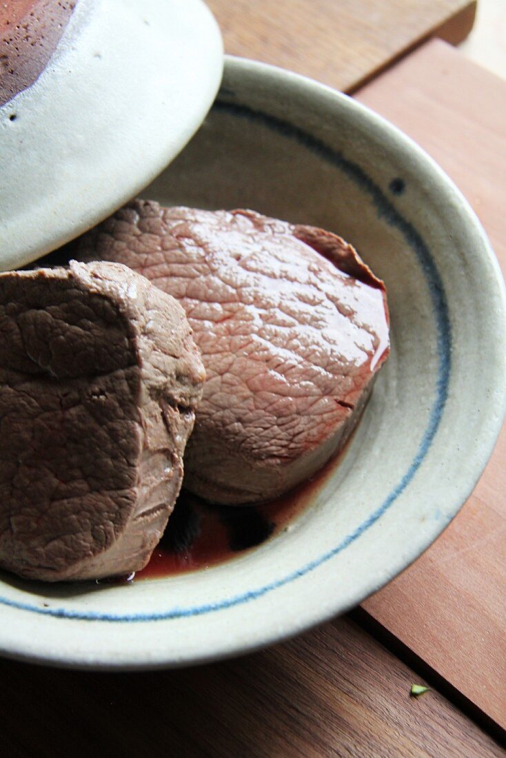 Two pieces of beef fillet in a bowl with a lid