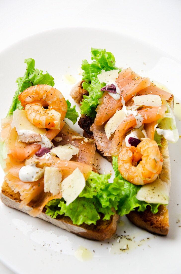 A slice of toast topped with salmon, prawns and Parmesan