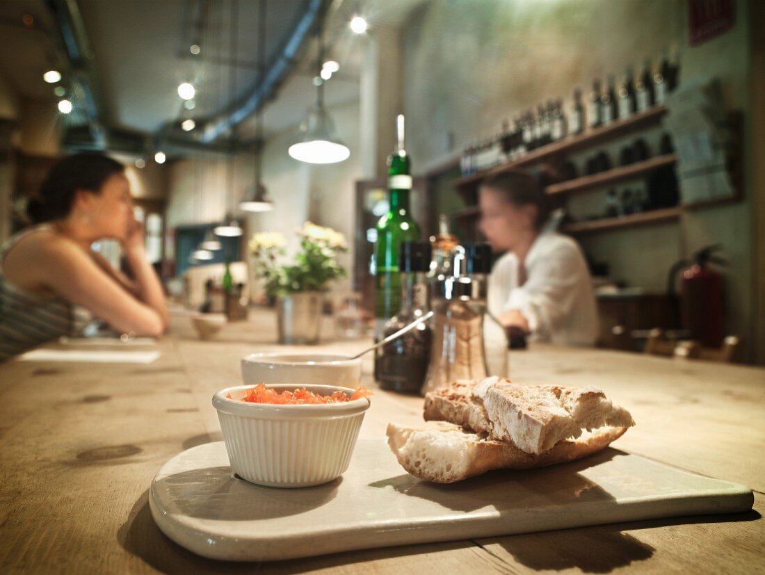 White bread and tomato spread in a pub with women in the background