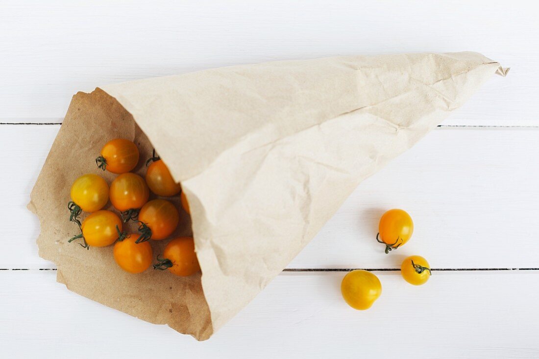 Yellow cherry tomatoes in a paper bag and next to it