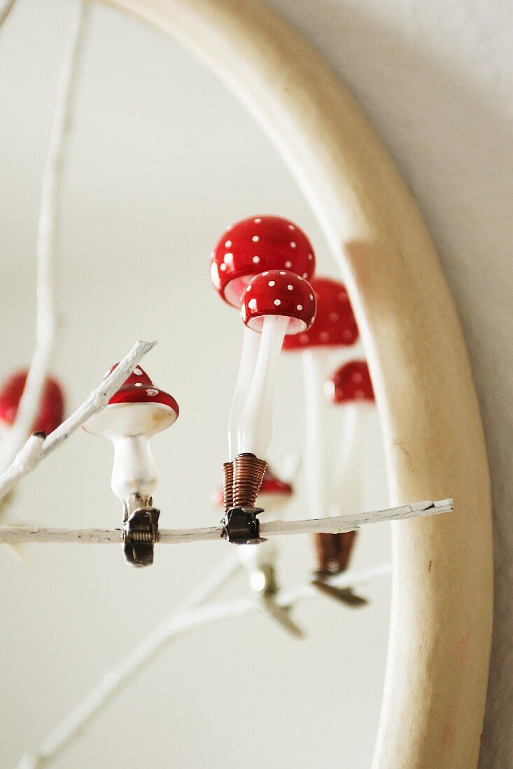 Glass toadstools on clips decorating a white-painted twig