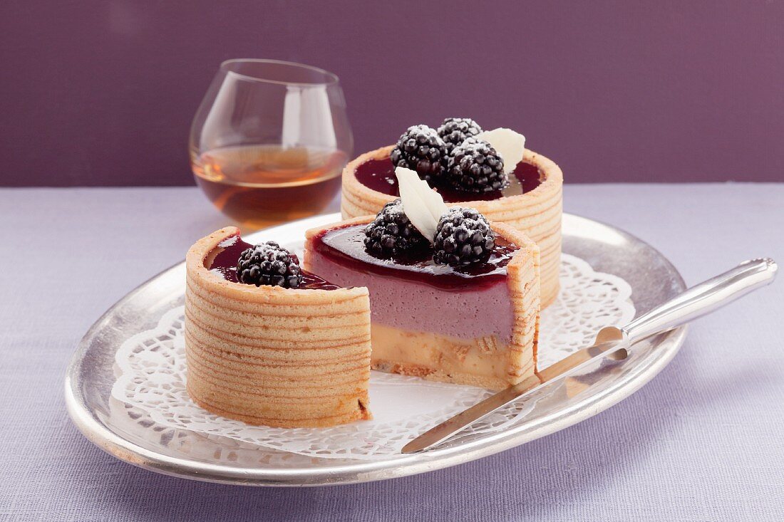 Two Baumkuchen (German layer cakes) filled with blackberry cream, and a glass of whisky