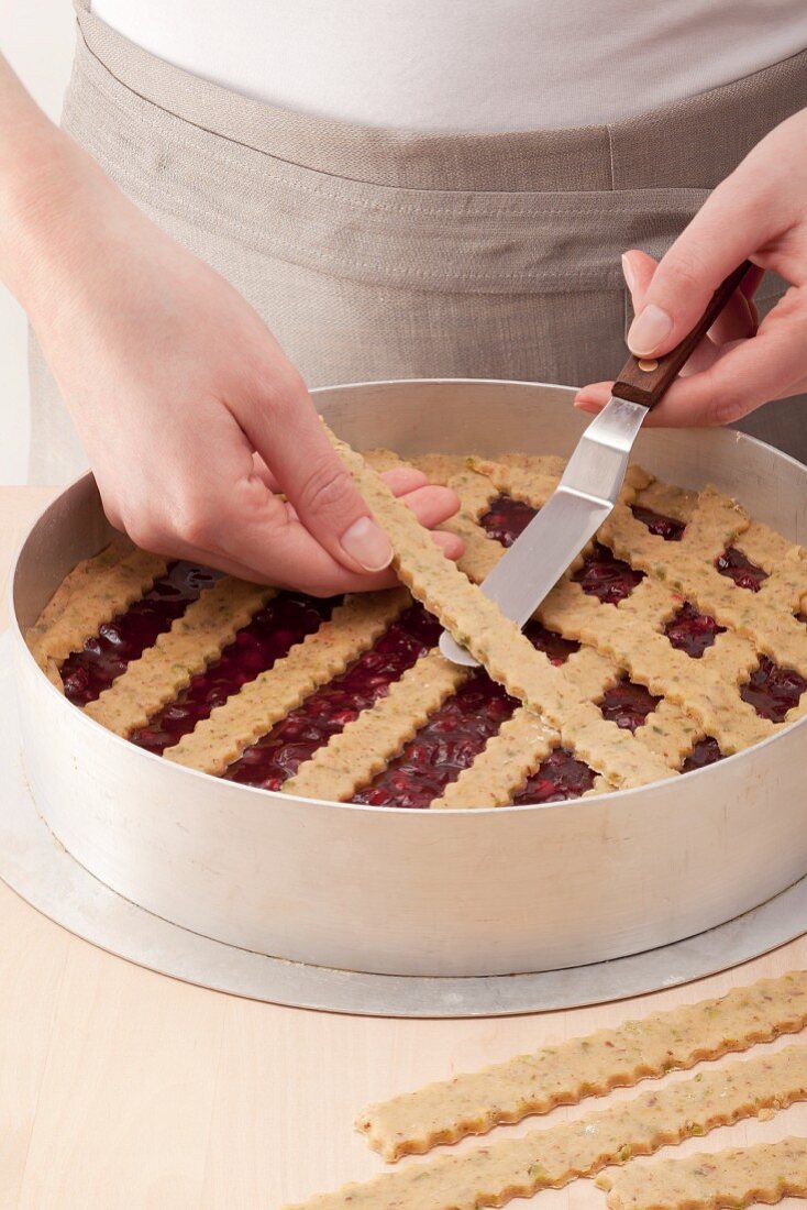 Lattice work being placed on a Linzer Torte (nut and jam layer cake)