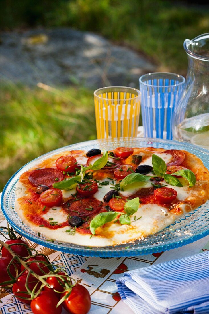 A tomato, mozzarella, sausage, olive and basil pizza