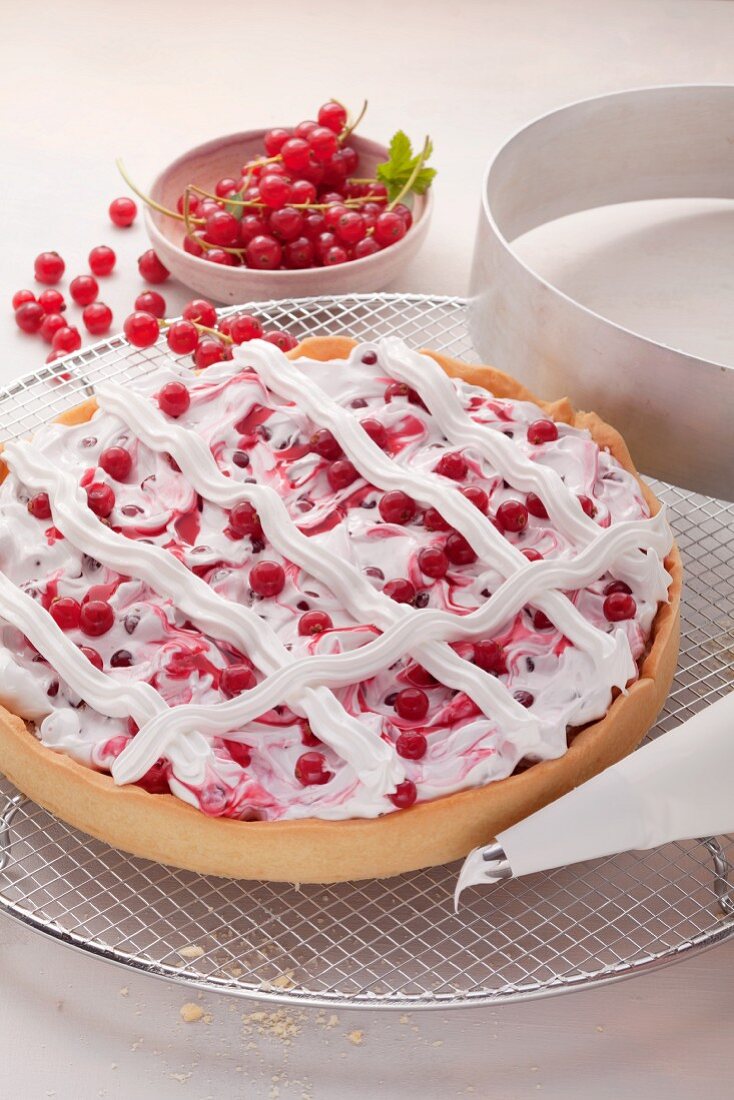 Redcurrant tart with meringue lattice; a cake ring and redcurrants in the background