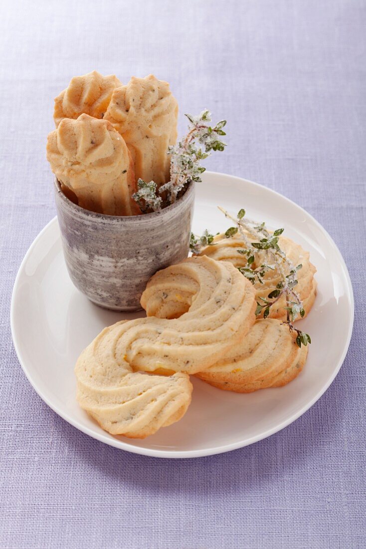 Piped biscuits with sprigs of thyme, on a white plate and in a cup