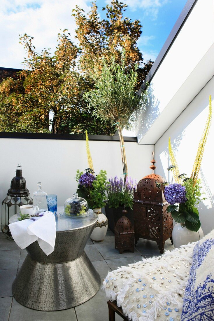 Roof terrace with Oriental furnishings - hammered metal table, Marrakesh lamps and sequinned upholstery in foreground
