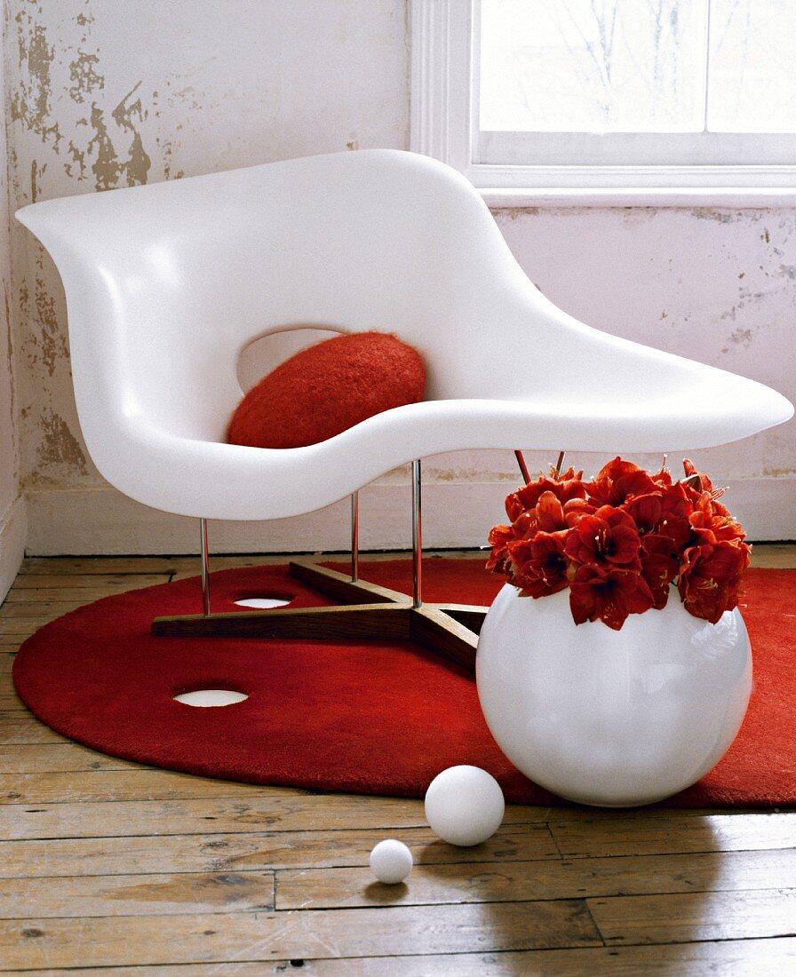 Sitting room detail with distressed walls, and a white moulded plastic chair on a round, red rug.