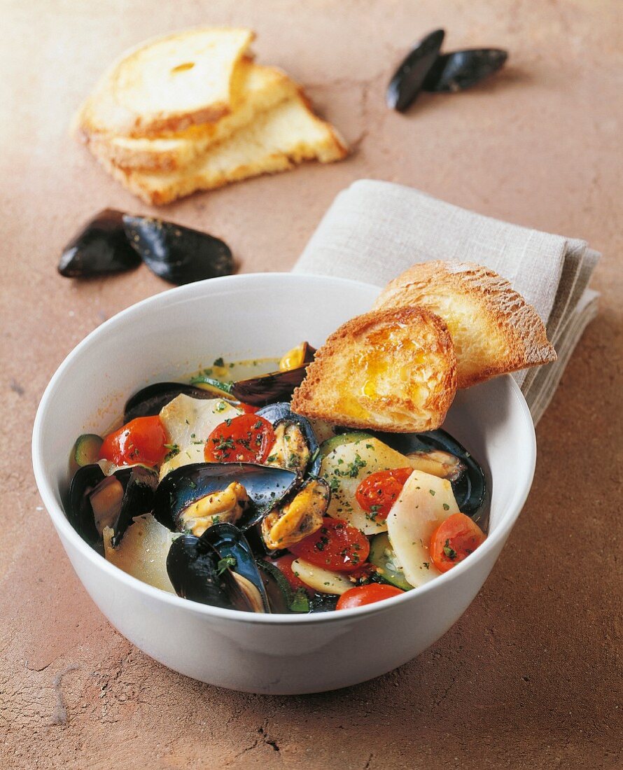 Potatoes soup with courgette, tomatoes and mussels