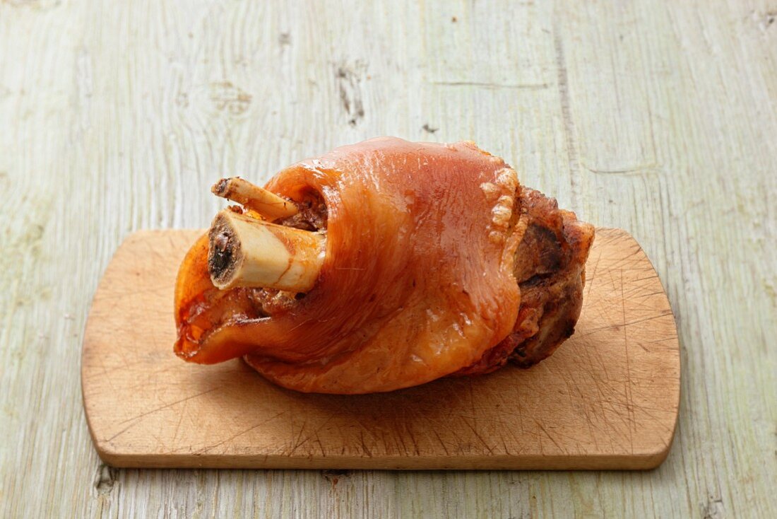 A pork knuckle on a chopping board