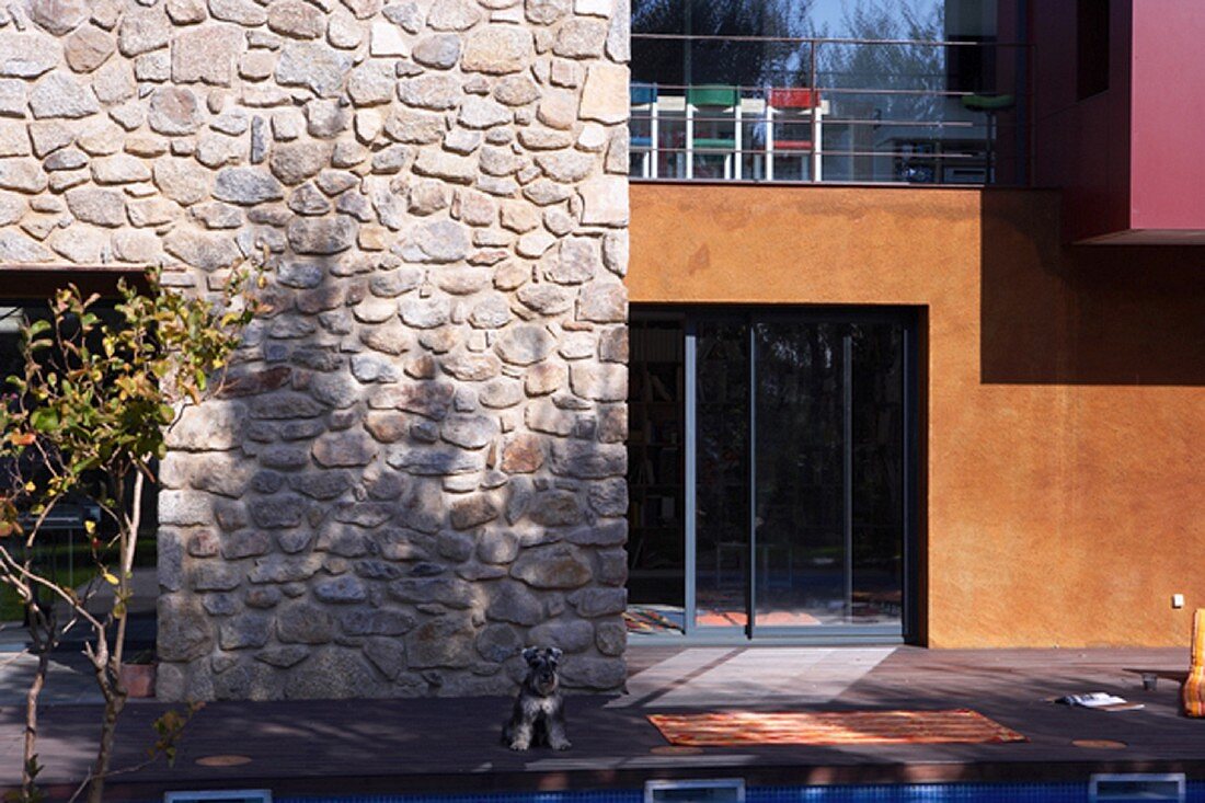 Moderne Hausfront mit rustikalem Naturstein, Glas und großen Farbflächen