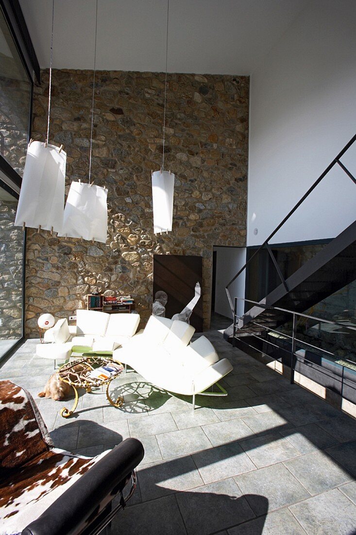 Modern, sunny living room with stone wall and original furniture