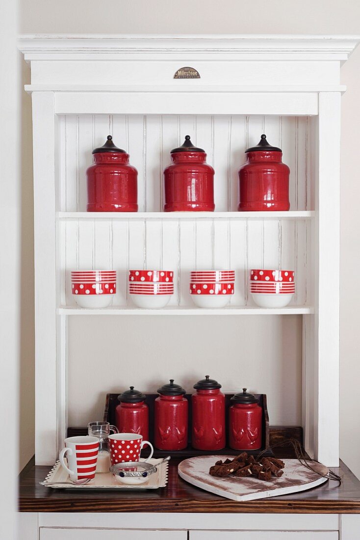 Rote Aufbewahrungsbehälter im Retrostil in weißem Regalaufsatz eines Küchenbuffets