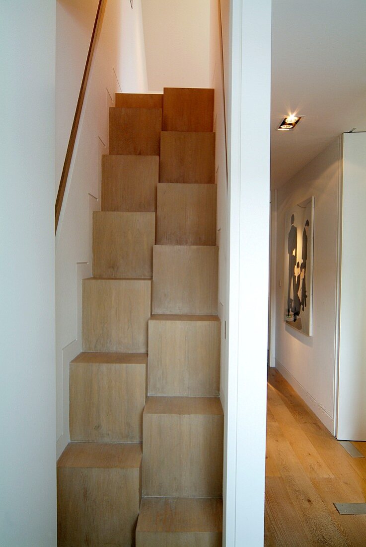 Space-saving staircase in narrow stairwell and view into modern hallway