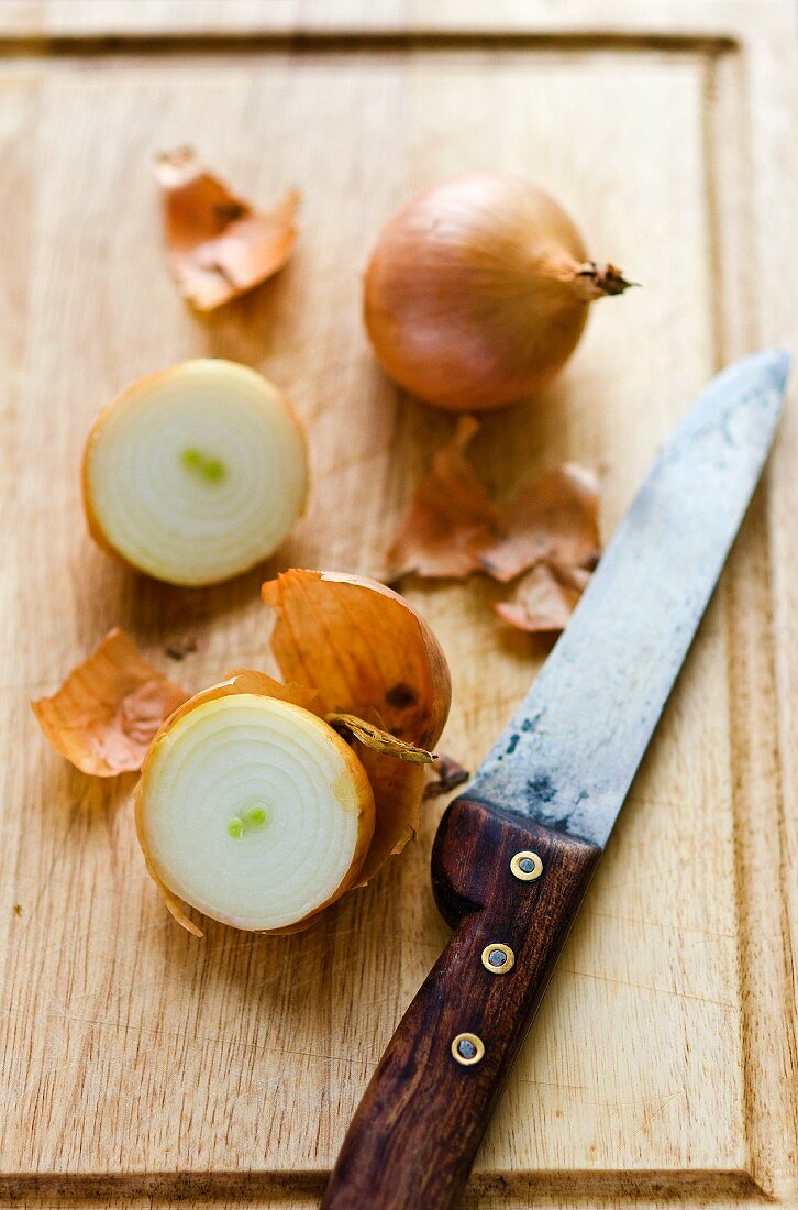 Onions, whole and halved, on a chopping board