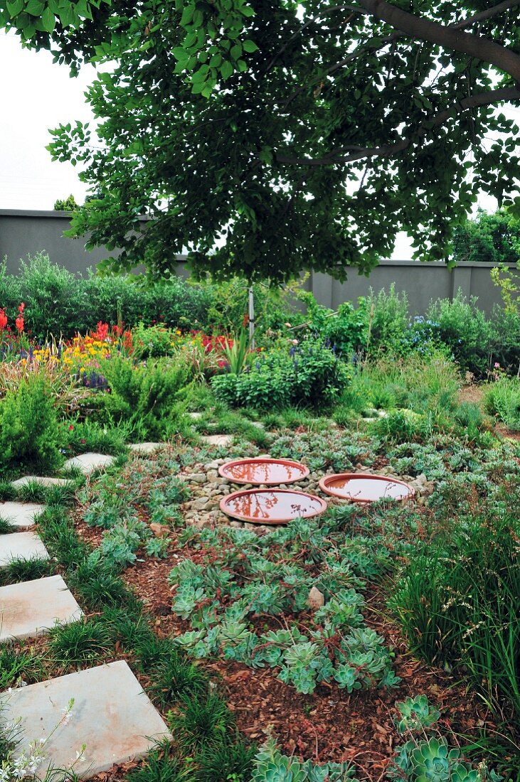 Garden with stone-flagged path & decorative dishes of water