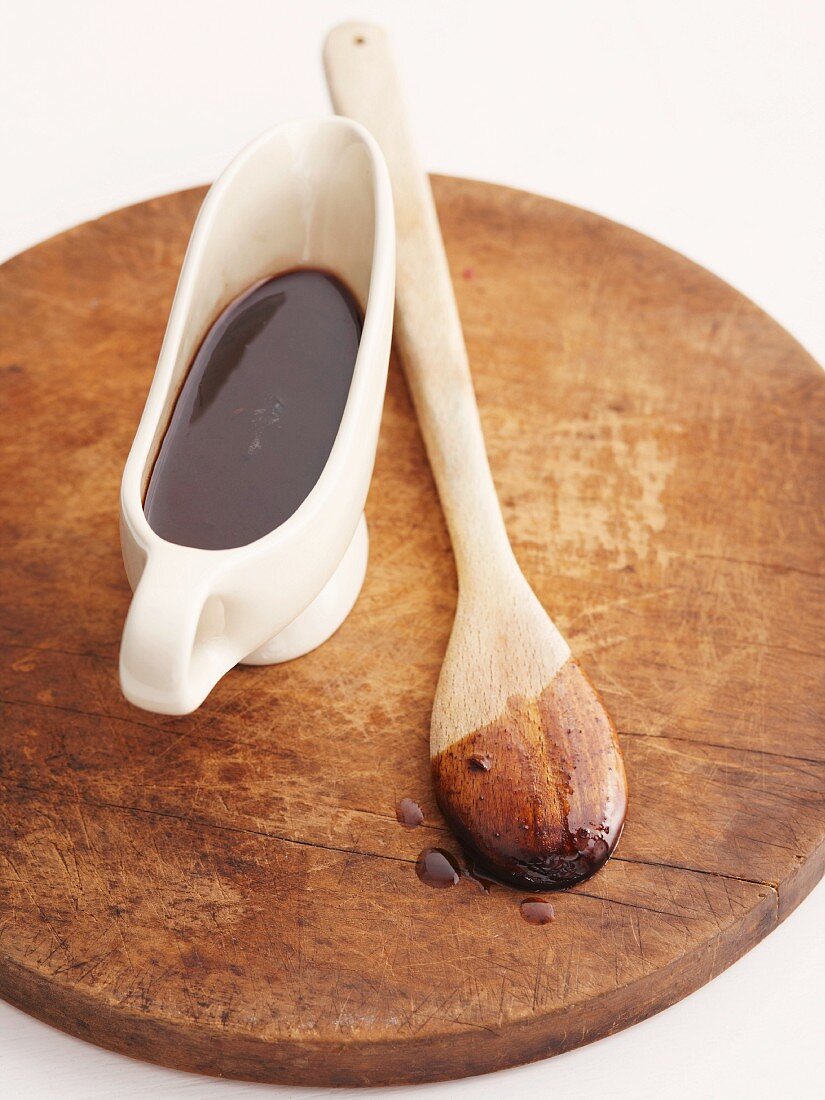 Port wine gravy in a gravy boar with a wooden spoon on a wooden chopping board