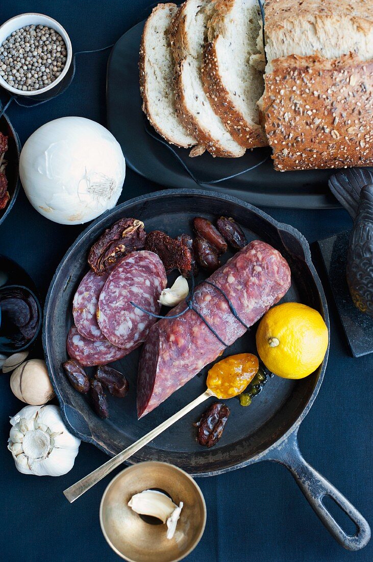 Zutatenstill mit Brot, Salami, Datteln, Gemüse & Gewürzen