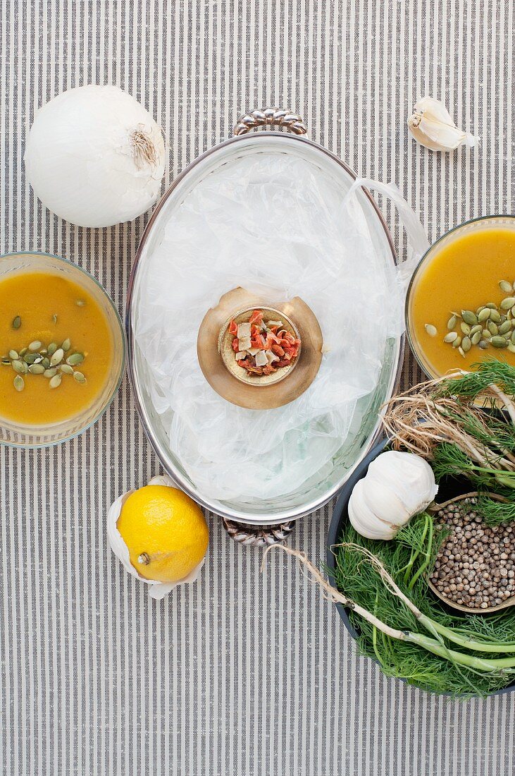 An arrangement of various ingredients and pumpkin soup in bowls