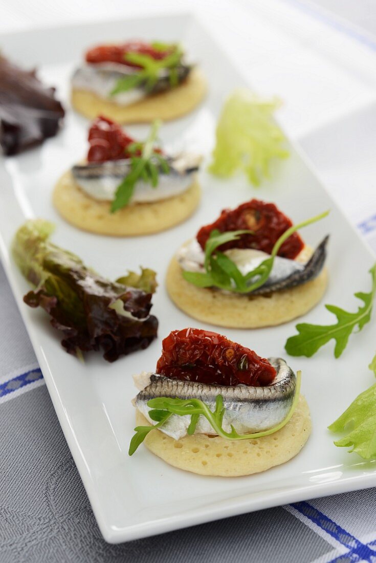 Blinis topped with anchovies and dried tomatoes