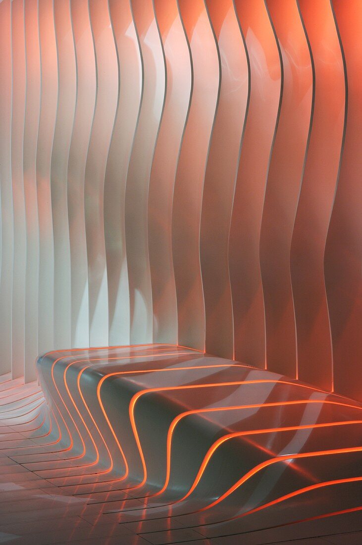 Slits backlit with coloured light in amorphous wall with integrated bench