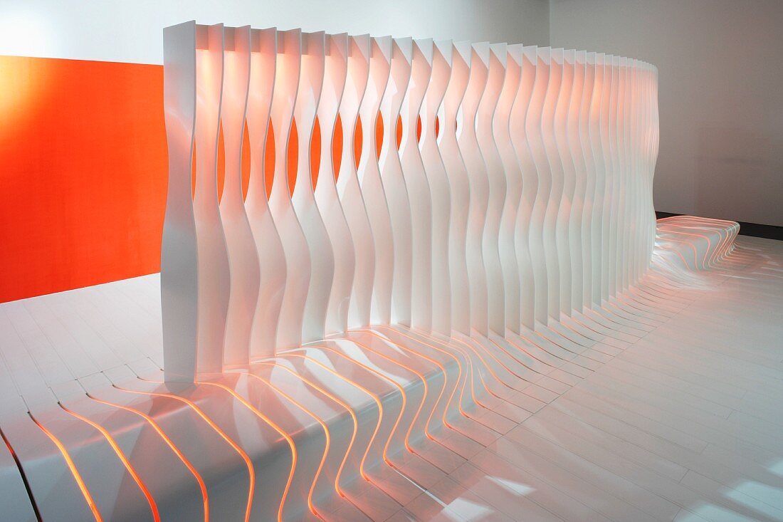 Partition with integrated bench made from shaped blades in front of wall with orange panel