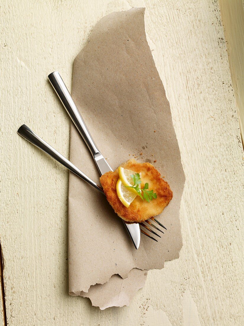 An escalope with lemon on a set of cutlery