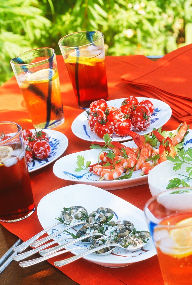 A table laid with snails, prawns, tomatoes and aperitifs