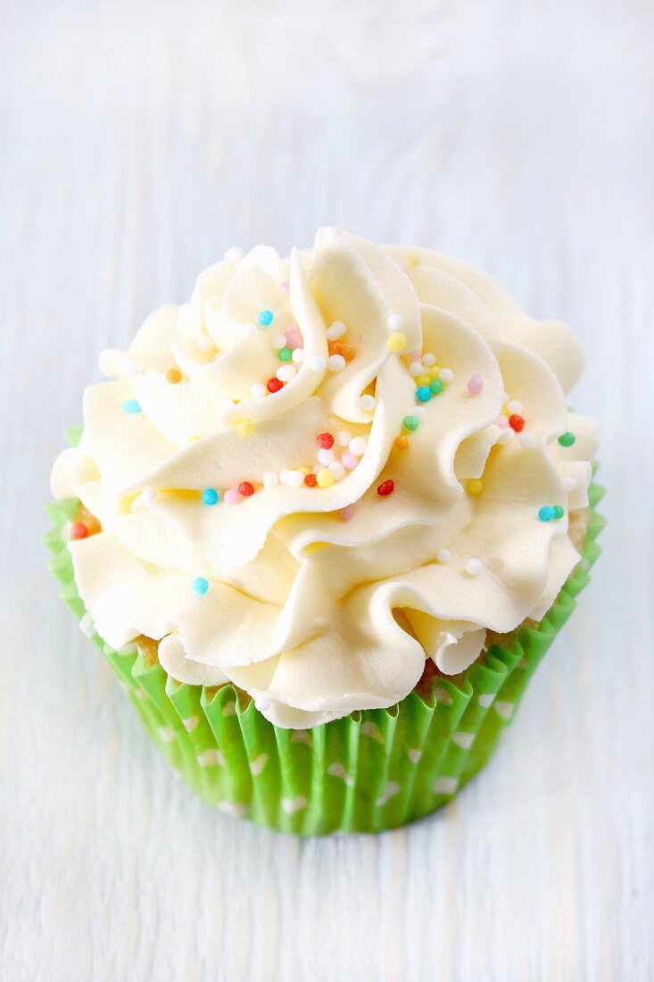 A cupcake topped with buttercream icing and sugar sprinkles