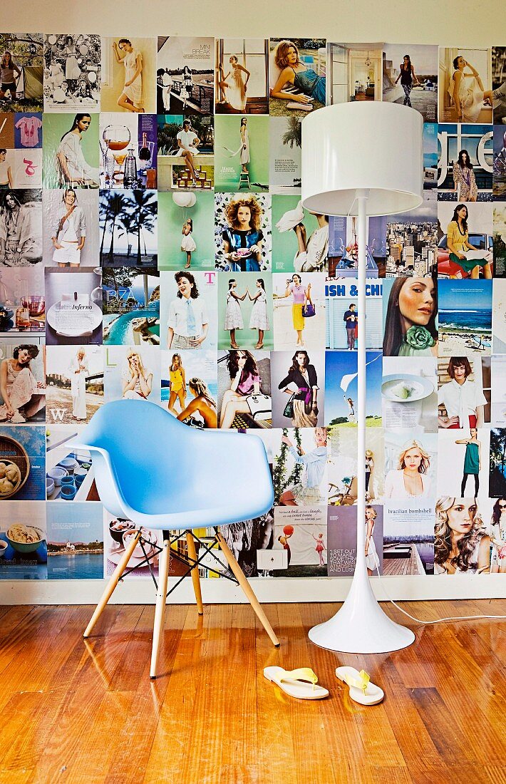 Pastel blue designer chair and white retro lamp in front of a large wall collage