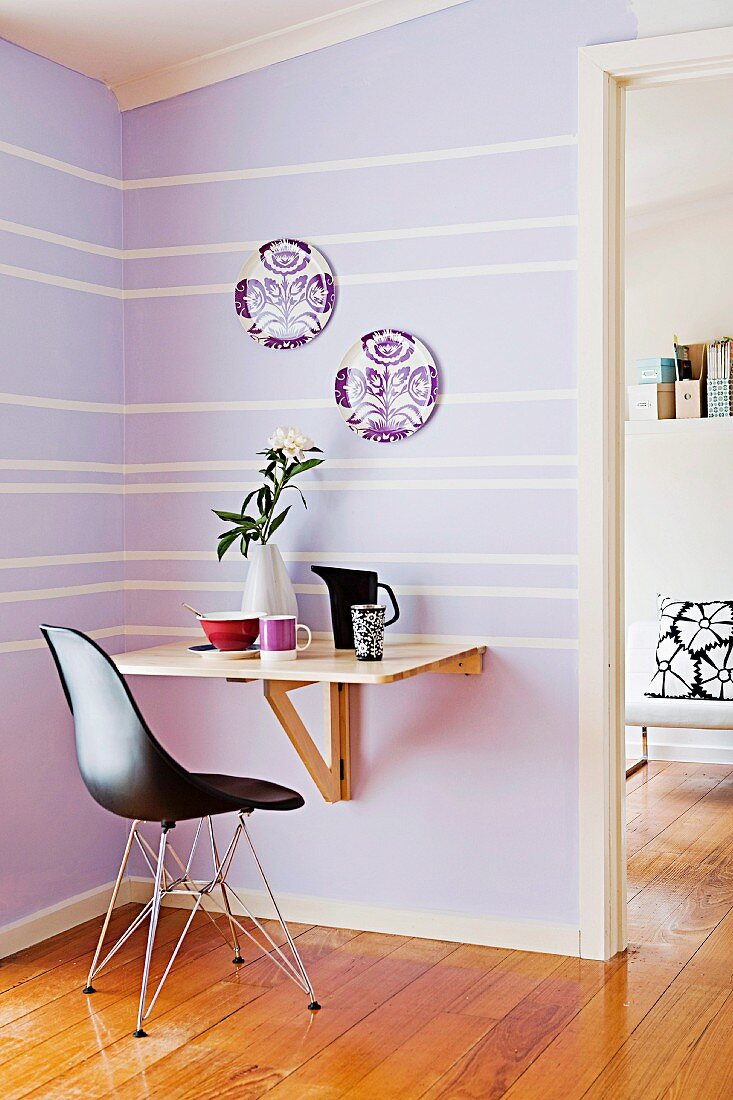 Small purple dining area with a simple folding table and black designer chair