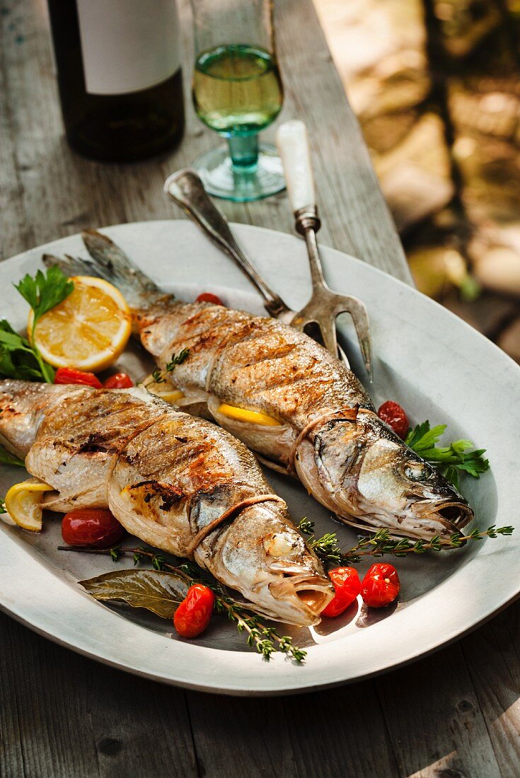 Two Whole Grilled Stuffed Branzino Fish on a Platter; On an Outdoor Table