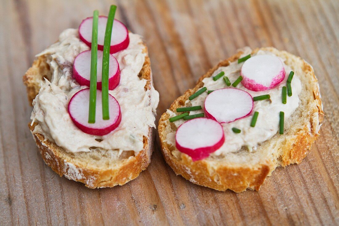 Bread topped with a spread, radishes and chives