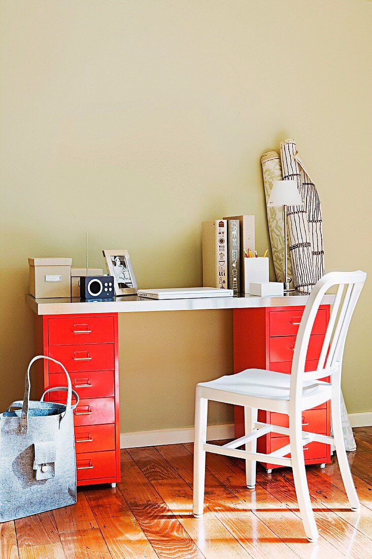 Writing surface on red metal containers on beige wall in sunny room