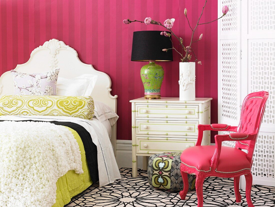 Romantisches Schlafzimmer mit Möbeln im Barockstil, auf der Schubladenkommode ein blühender Magnolienzweig vor gestreifter Tapete