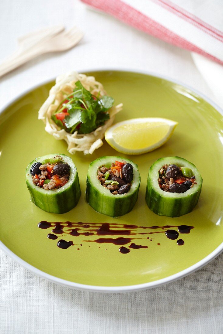 Steamed cucumber slices with soya mince filling, served on a green plate with fried rice noodles with coriander