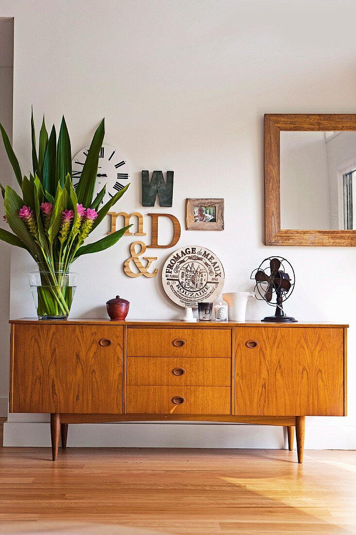 Letter-shaped ornaments, bouquet and fan on 50s retro sideboard
