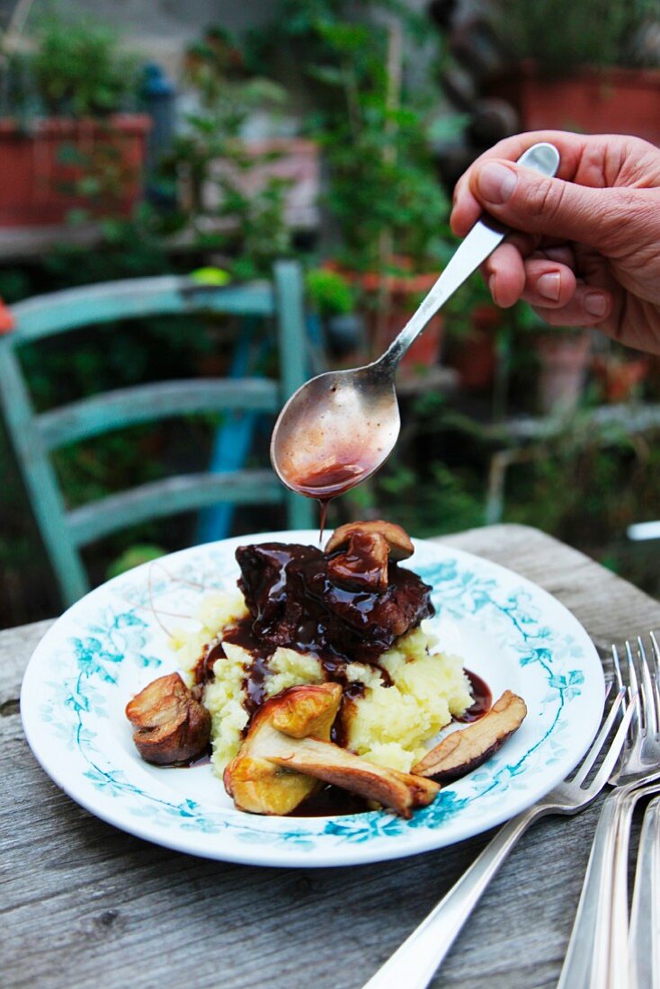 Veal cheeks on a bed of mashed potatoes with mushrooms and sauce