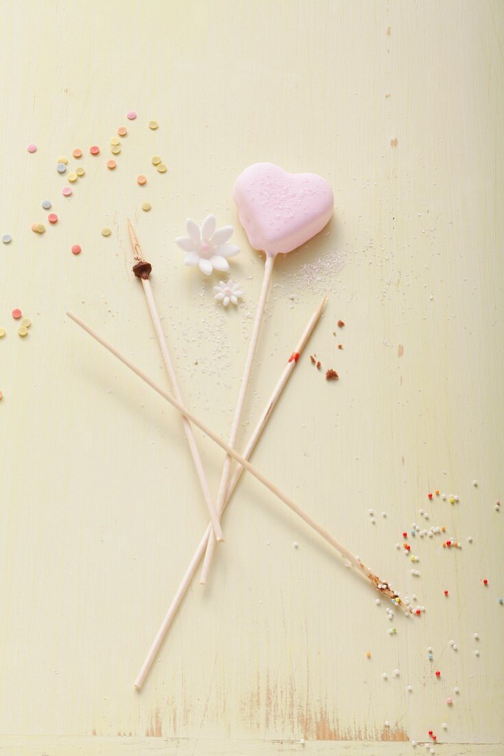 A heart-shaped cake pop and wooden sticks