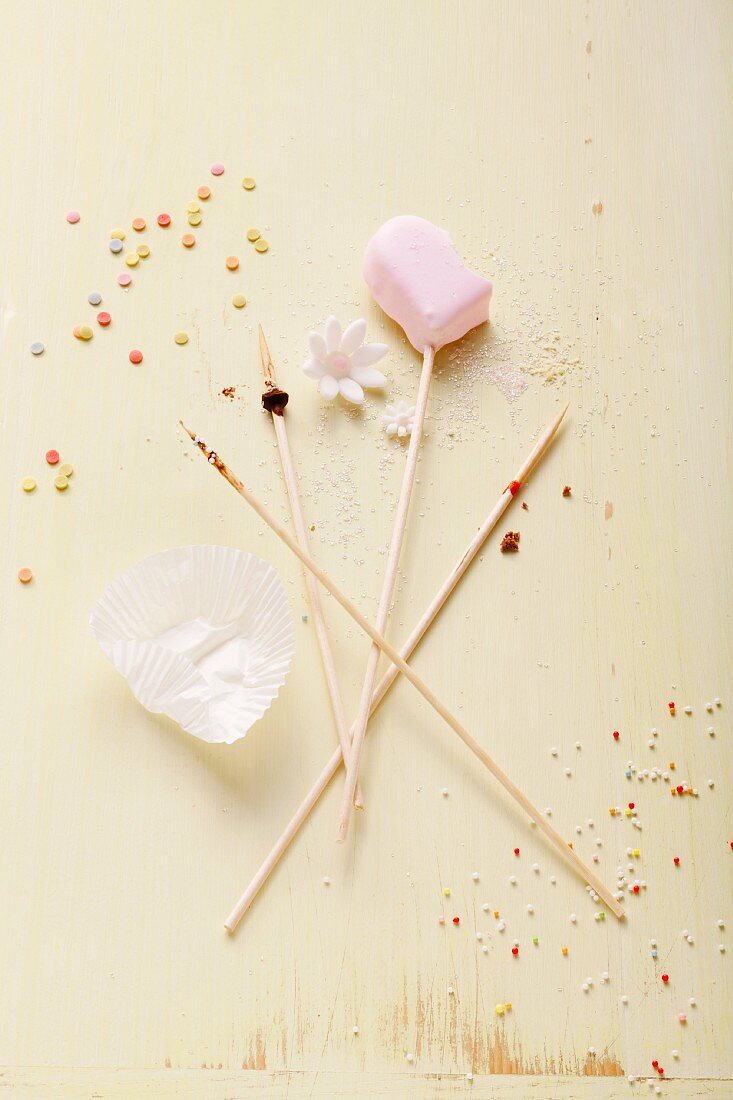 A heart-shaped cake pop and four wooden sticks
