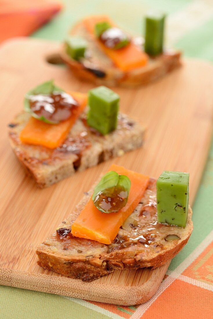 Slices of bread topped with mimolette, pesto gouda and fig chutney