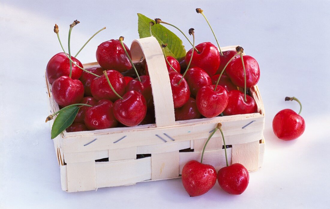 A wooden basket of sweet cherries