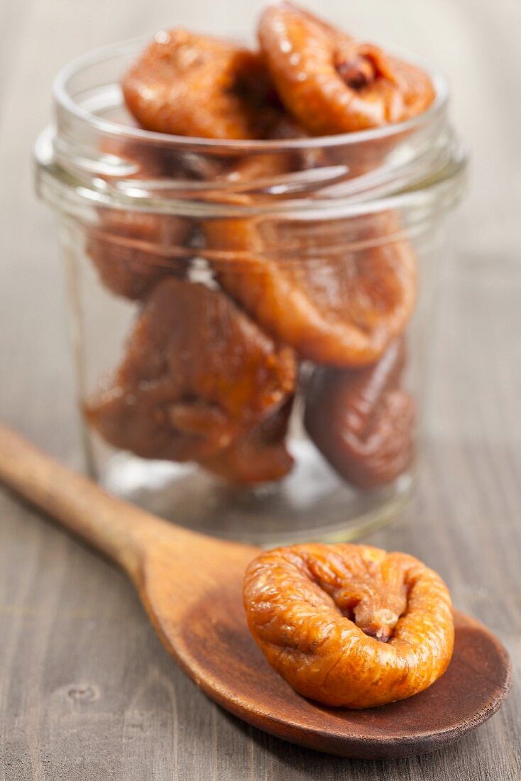 Dried figs on a wooden spoon and in a jar
