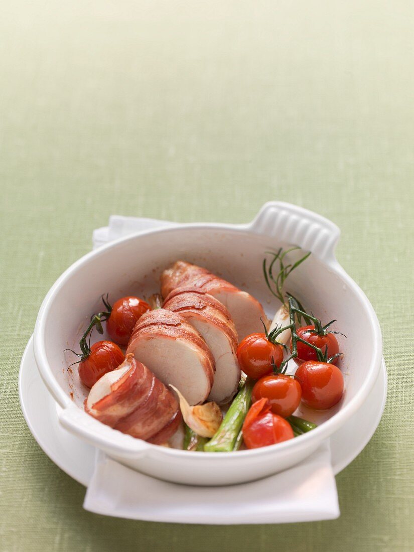 Chicken breast wrapped in ham with cherry tomatoes and spring onions