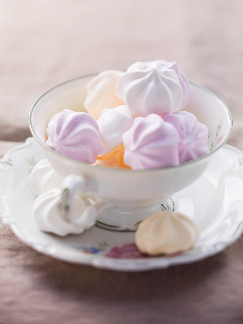 Various coloured meringues in a cup and on a saucer