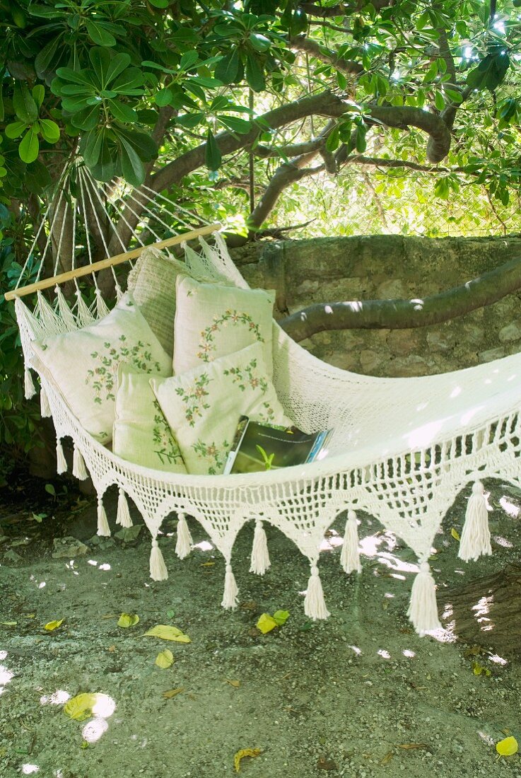 Cosy garden corner - hammock with cushions in front of garden wall