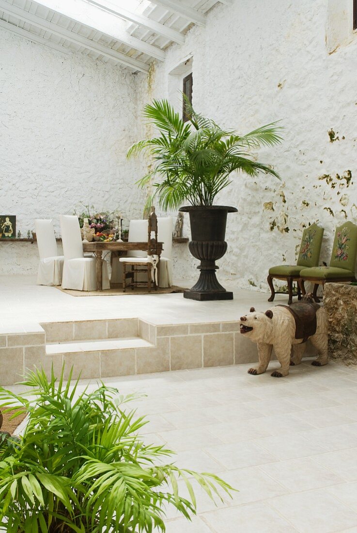 Mediterrane Loggia mit Palmentopf vor Sitzplatz auf Podest