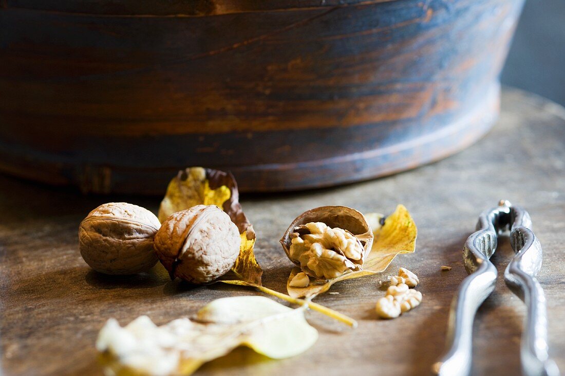 Whole and cracked walnuts with a nutcracker