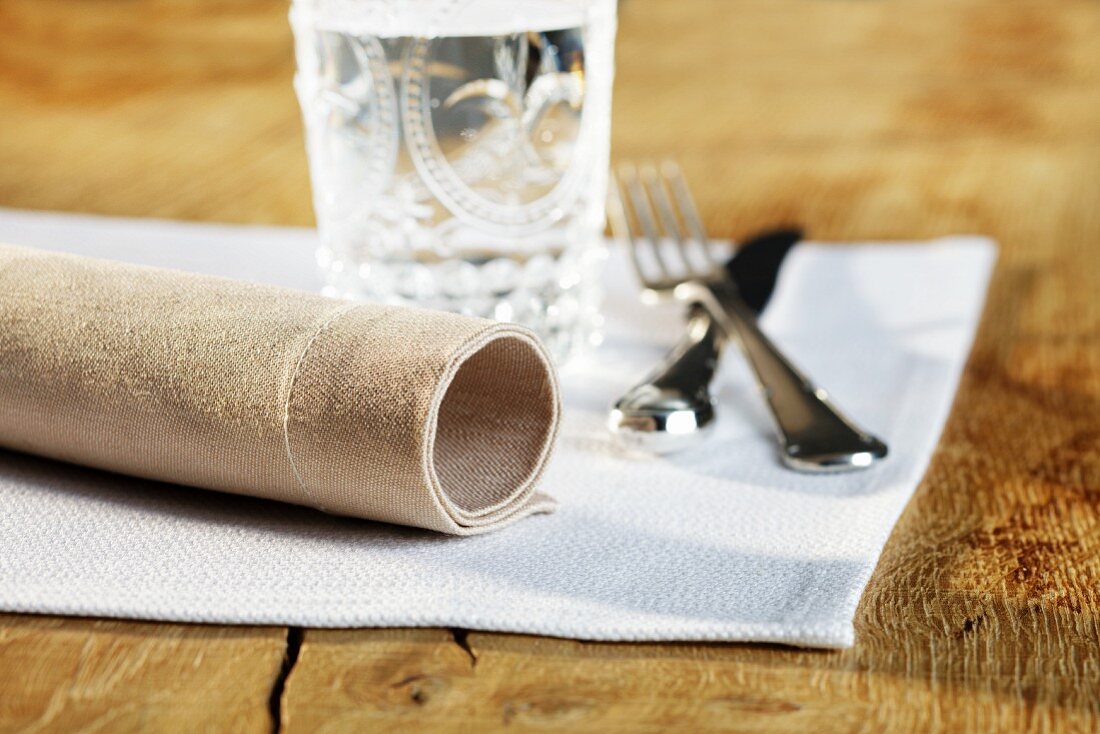 A place setting with a napkin, cutlery and a glass of water