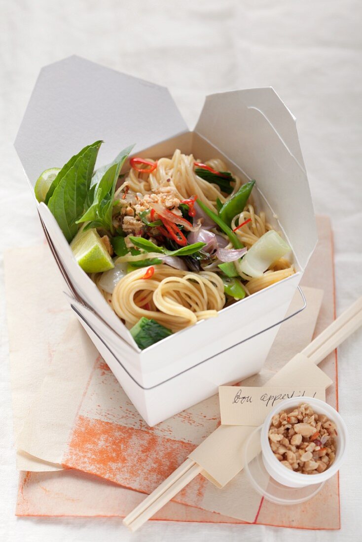 A box of noodles with bok choy and peanuts